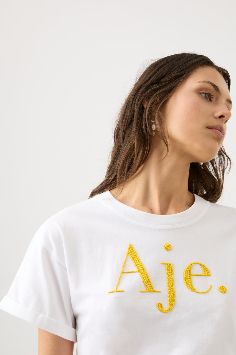 Remi Embellished Logo Tee | White Sunshine Yellow Logo | Aje